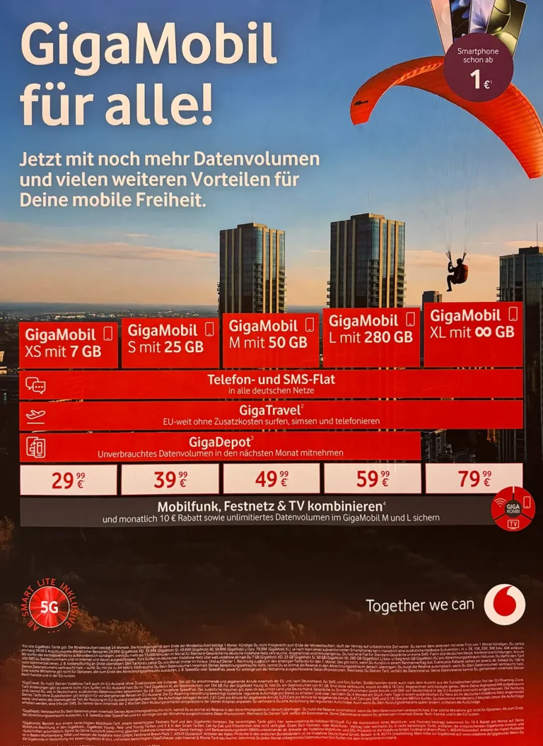 Farbiges Vodafone-Werbeplakat mit dem Titel „Die neuen GigaMobil Tarife“. Darstellung von fünf Tarifoptionen (XS, S, M, L, XL) mit unterschiedlichem Datenvolumen von 7 GB bis unbegrenzt, Preisen ab 29,99 € bis 79,99 € pro Monat. Zusätzliche Vorteile wie Allnet-Flat für Telefonie & SMS, EU-Roaming mit GigaTravel und GigaDepot werden genannt. Rechts im Bild telefoniert ein Mann im Freien, unten sind die Rückansicht von Hundeohren und ein Sonnenuntergang zu sehen. Vodafone-Logo und Slogan „Together we can“ unten rechts.