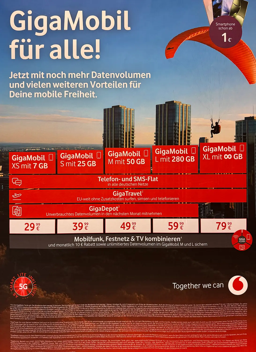 Farbiges Vodafone-Werbeplakat mit dem Titel „Die neuen GigaMobil Tarife“. Darstellung von fünf Tarifoptionen (XS, S, M, L, XL) mit unterschiedlichem Datenvolumen von 7 GB bis unbegrenzt, Preisen ab 29,99 € bis 79,99 € pro Monat. Zusätzliche Vorteile wie Allnet-Flat für Telefonie & SMS, EU-Roaming mit GigaTravel und GigaDepot werden genannt. Rechts im Bild telefoniert ein Mann im Freien, unten sind die Rückansicht von Hundeohren und ein Sonnenuntergang zu sehen. Vodafone-Logo und Slogan „Together we can“ unten rechts.